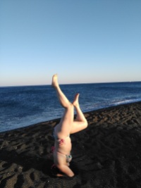 Practicing headstands on black sand